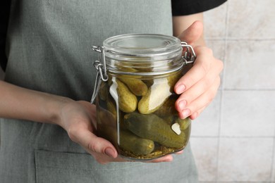 Woman holding jar with pickled cucumbers indoors, closeup