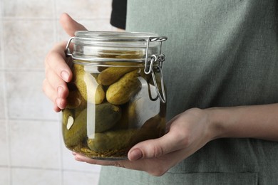 Woman holding jar with pickled cucumbers indoors, closeup