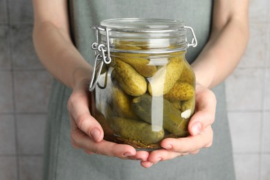 Woman holding jar with pickled cucumbers indoors, closeup