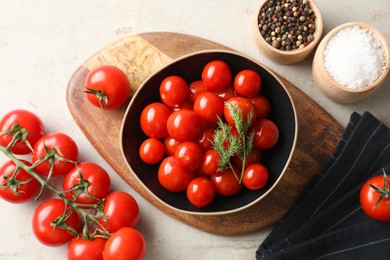 Tasty pickled tomatoes in bowl, spices and fresh vegetables on light grey table, top view