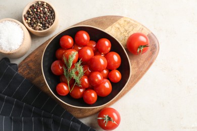 Tasty pickled tomatoes in bowl, spices and fresh vegetables on light grey table, top view