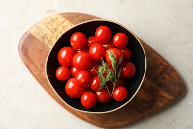 Tasty pickled tomatoes and dill in bowl on light grey table, top view