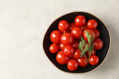 Tasty pickled tomatoes and dill in bowl on light grey table, top view. Space for text