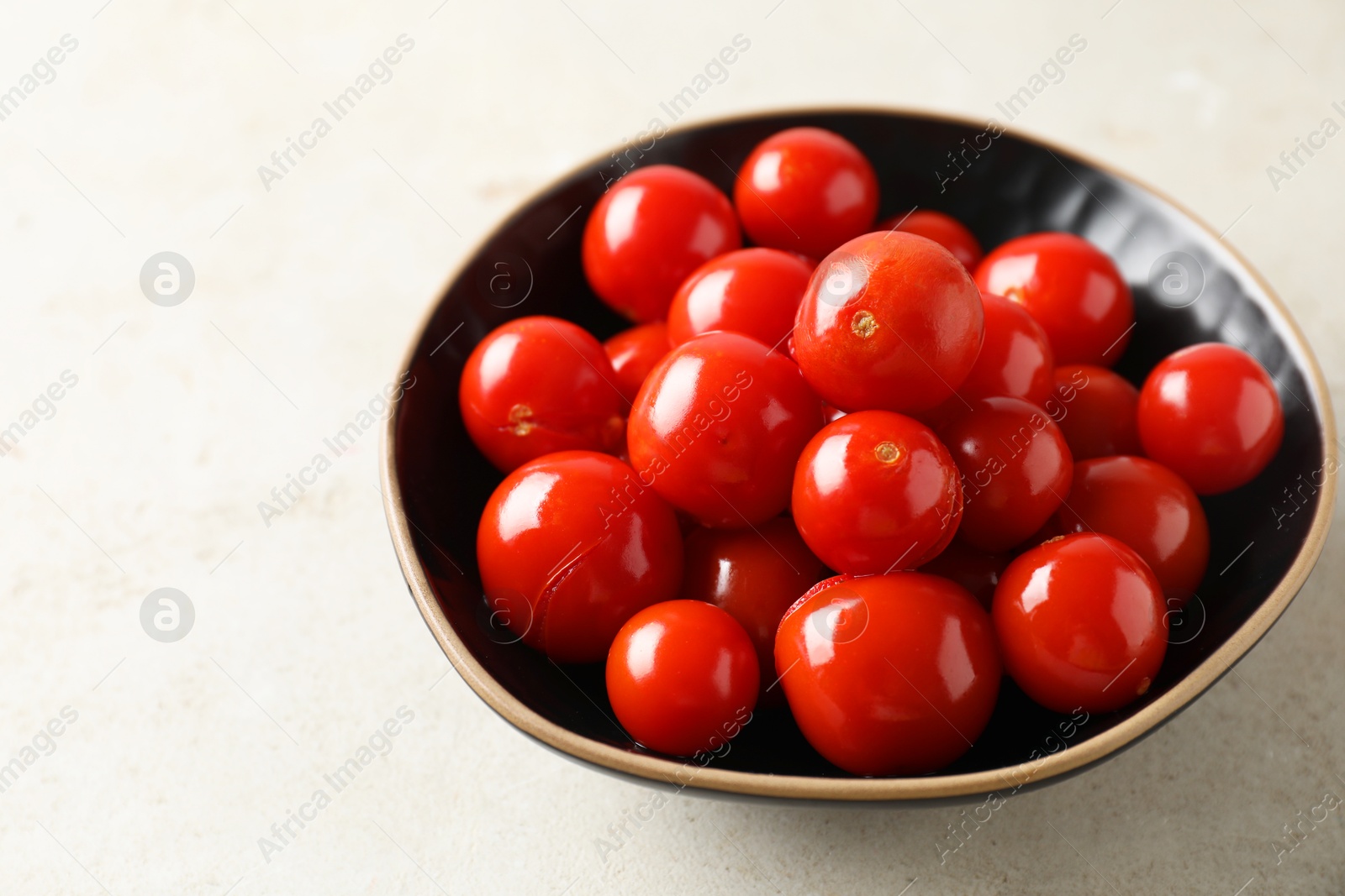 Photo of Tasty pickled tomatoes in bowl on light grey table