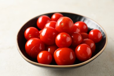 Photo of Tasty pickled tomatoes in bowl on light grey table, closeup