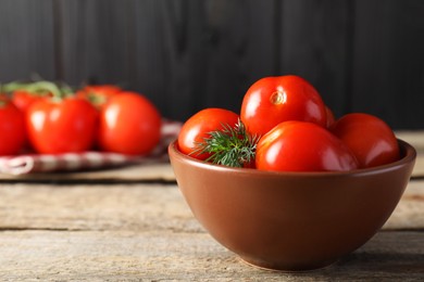 Tasty pickled tomatoes and dill in bowl on wooden table, space for text