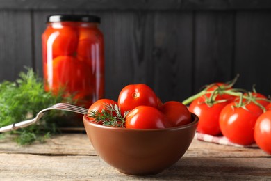 Tasty pickled tomatoes, dill, fresh vegetables and fork on wooden table