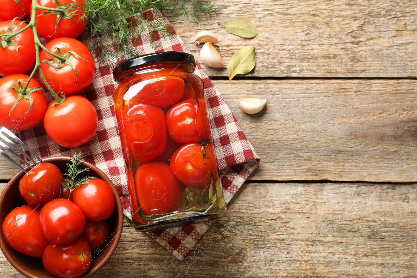 Photo of Tasty pickled tomatoes in jar, spices and fresh vegetables on wooden table, top view. Space for text