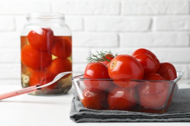 Tasty pickled tomatoes and dill in bowl on white table