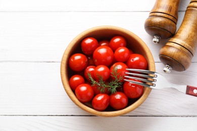 Tasty pickled tomatoes, dill and fork on white wooden table, top view. Space for text