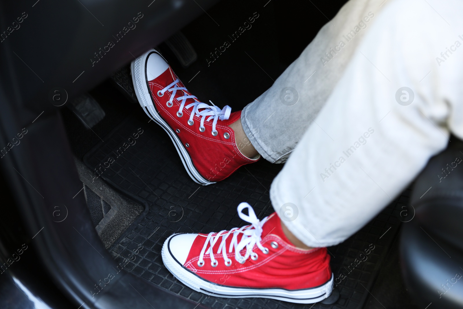 Photo of Woman in sneakers pushing on pedal of car brake, closeup