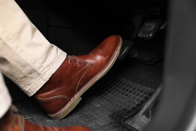 Photo of Man pushing on pedal of car brake, closeup