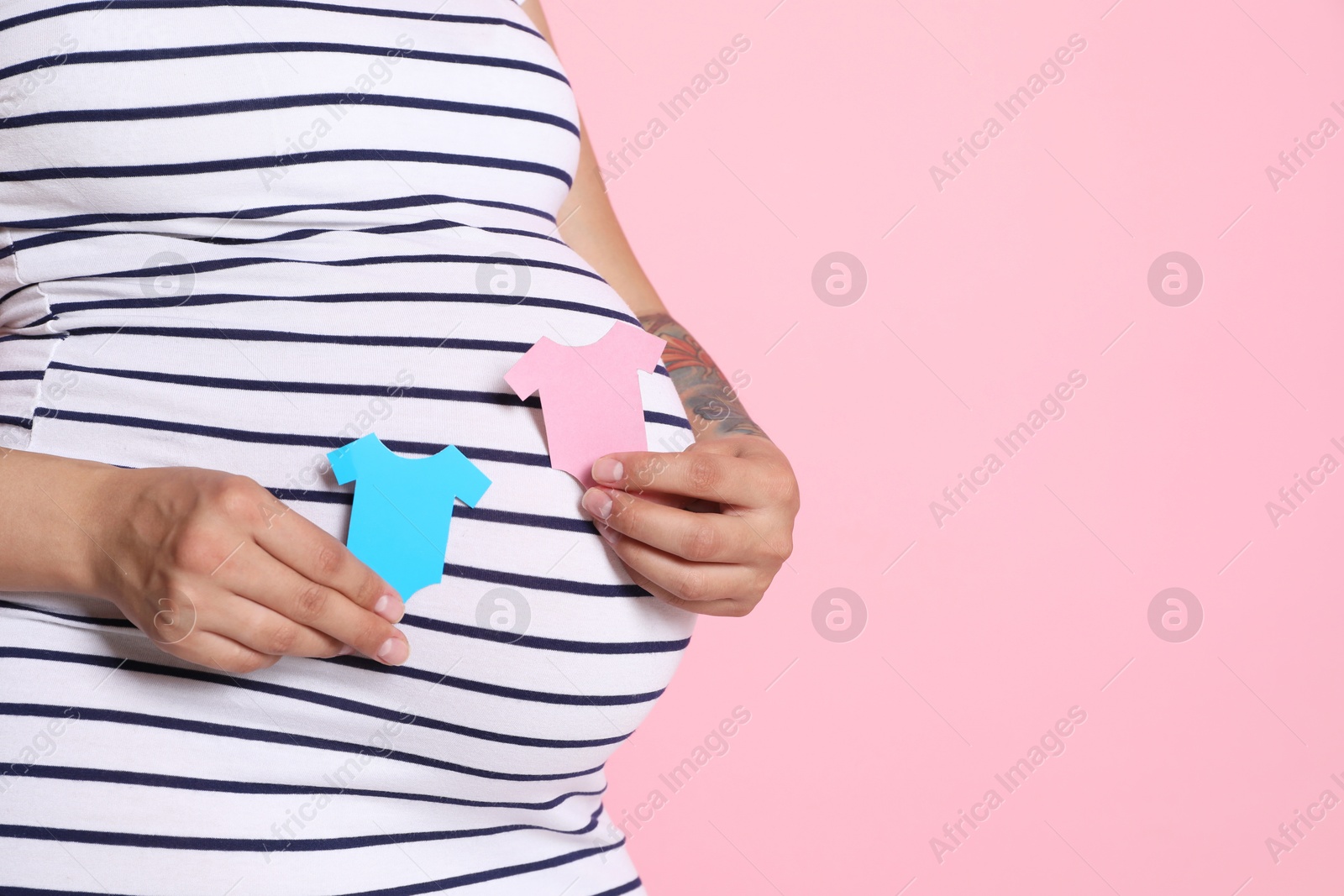 Photo of Pregnant woman with paper hearts on pink background, closeup and space for text. Expecting twins