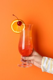 Photo of Woman with glass of refreshing cocktail on orange background, closeup