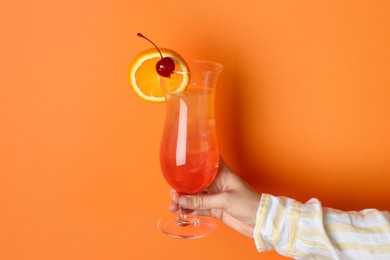 Photo of Woman with glass of refreshing cocktail on orange background, closeup