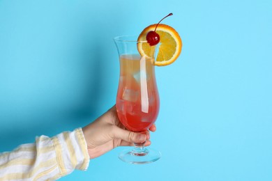 Photo of Woman with glass of refreshing cocktail on light blue background, closeup