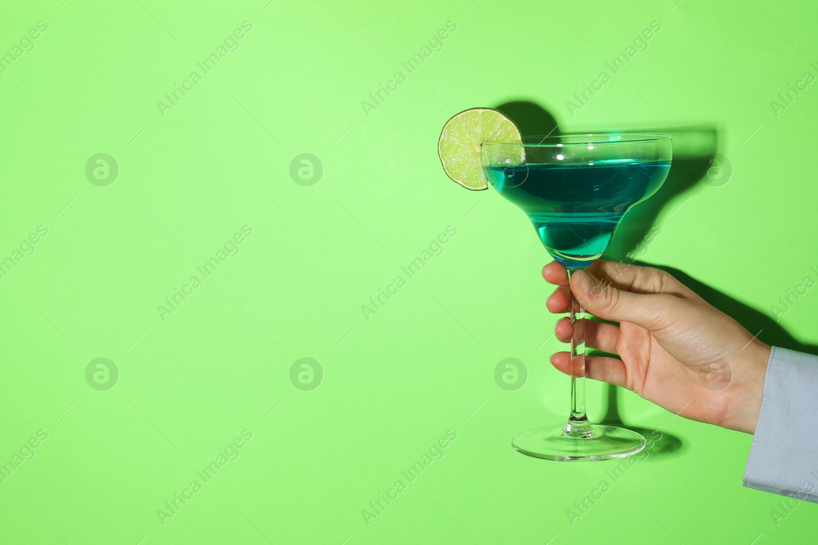 Photo of Woman with glass of refreshing cocktail on green background, closeup. Space for text