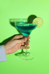 Photo of Woman with glass of refreshing cocktail on green background, closeup