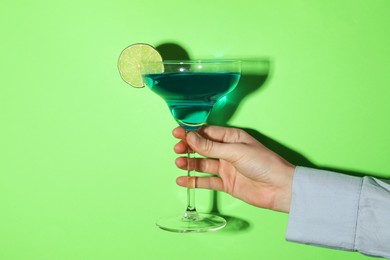 Photo of Woman with glass of refreshing cocktail on green background, closeup