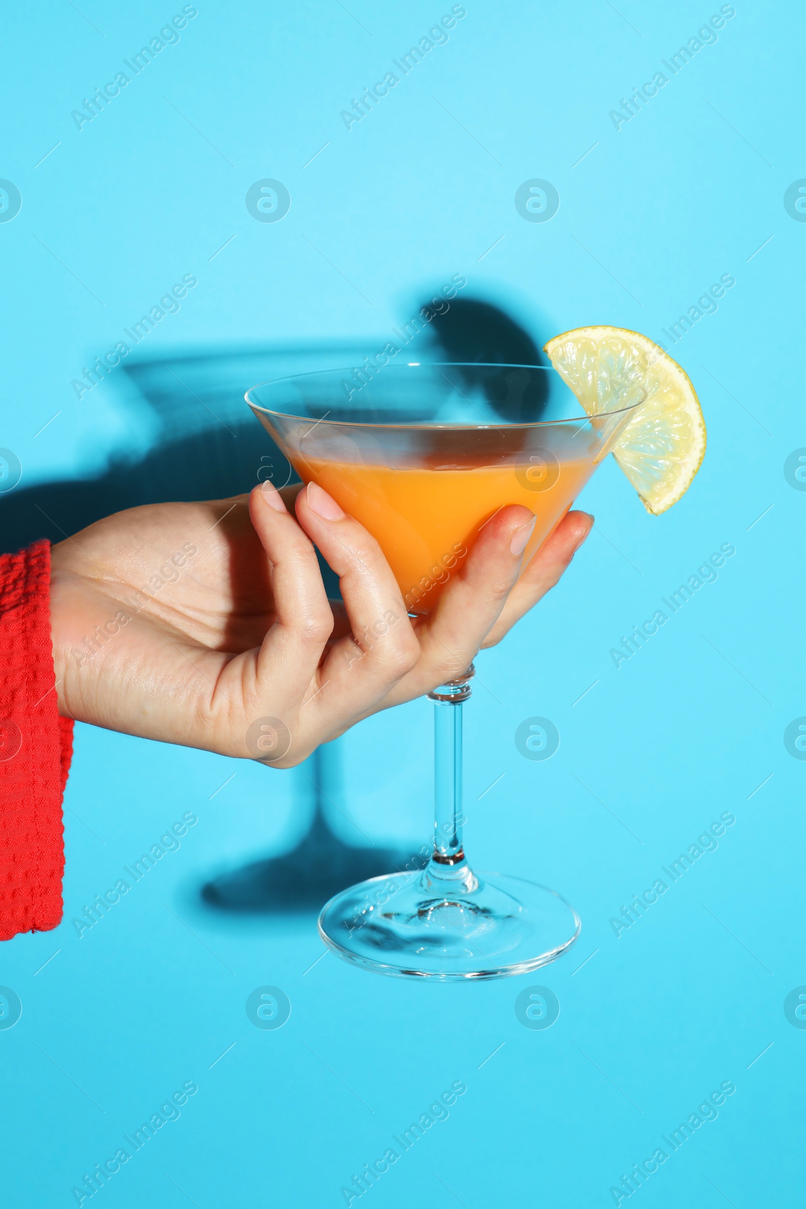 Photo of Woman with glass of refreshing cocktail on light blue background, closeup