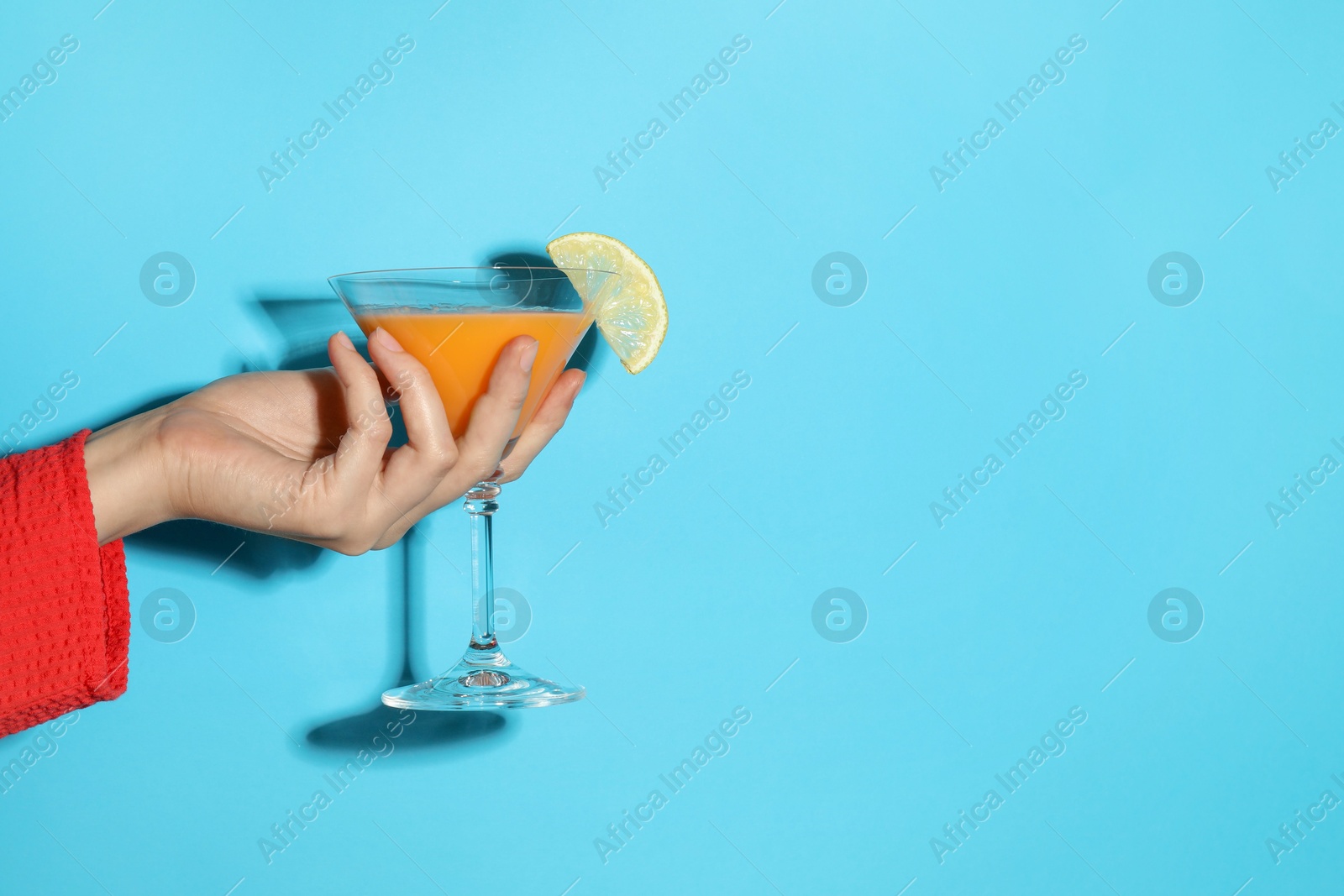 Photo of Woman with glass of refreshing cocktail on light blue background, closeup