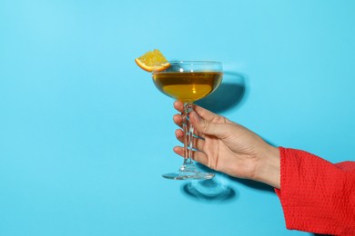 Photo of Woman with glass of refreshing cocktail on light blue background, closeup