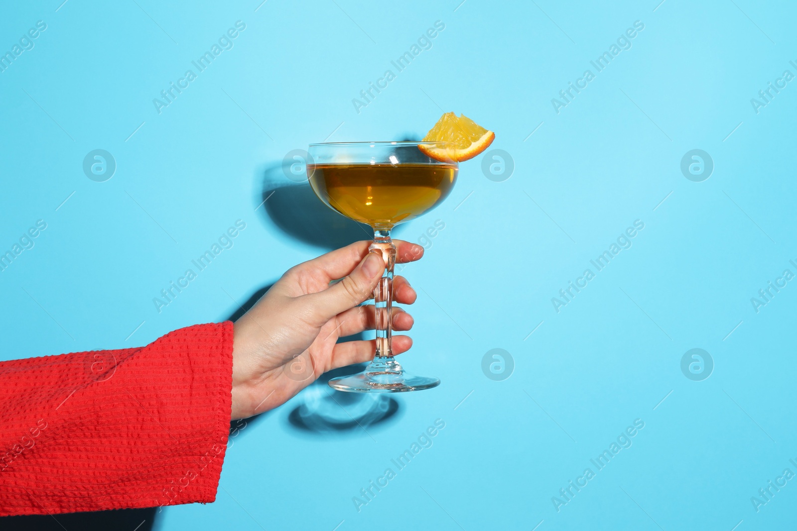 Photo of Woman with glass of refreshing cocktail on light blue background, closeup