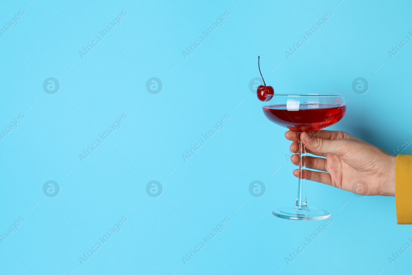 Photo of Woman with glass of refreshing cocktail on light blue background, closeup