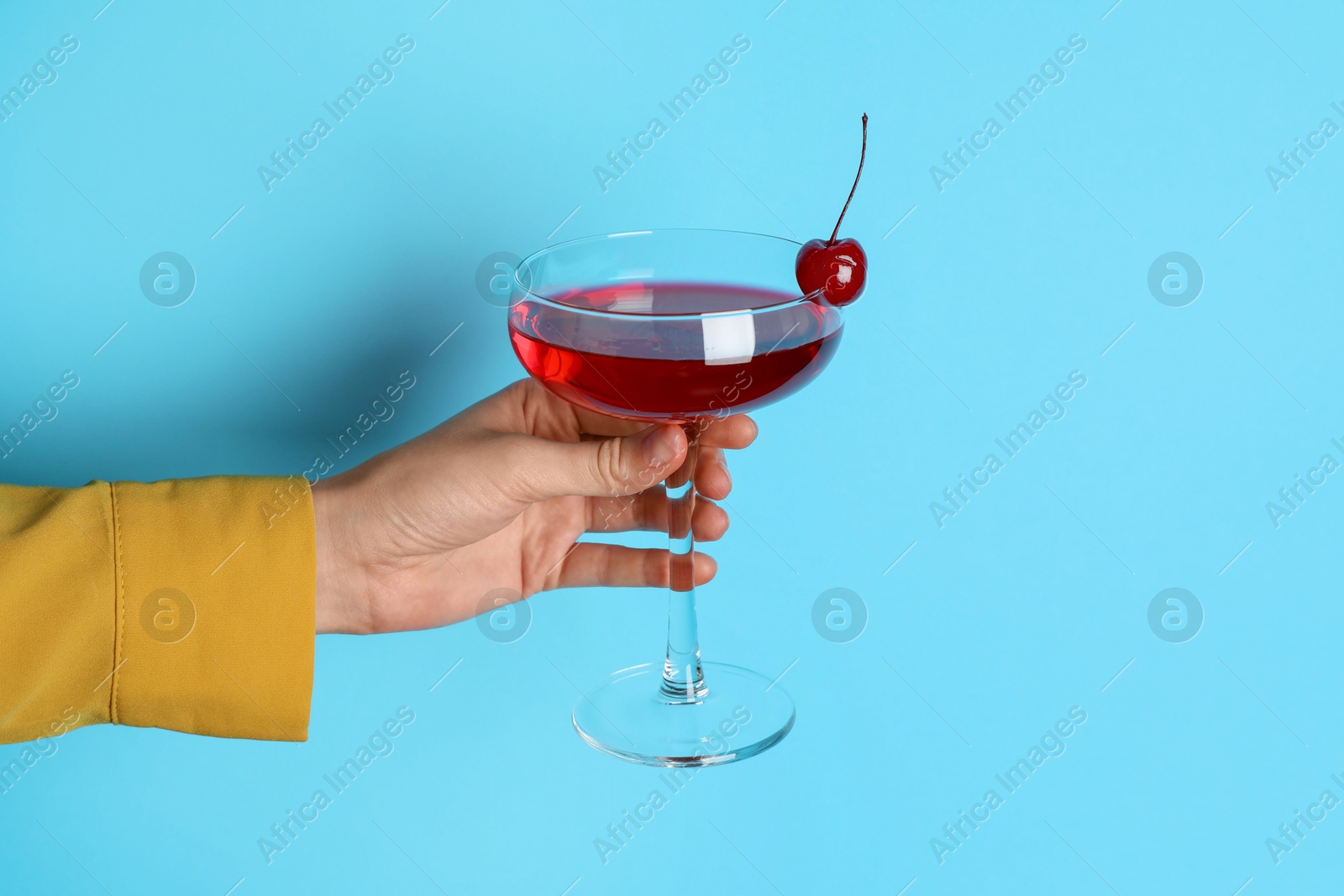 Photo of Woman with glass of refreshing cocktail on light blue background, closeup