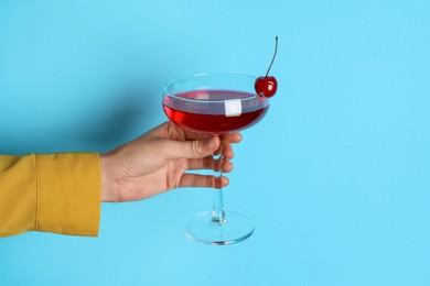 Photo of Woman with glass of refreshing cocktail on light blue background, closeup