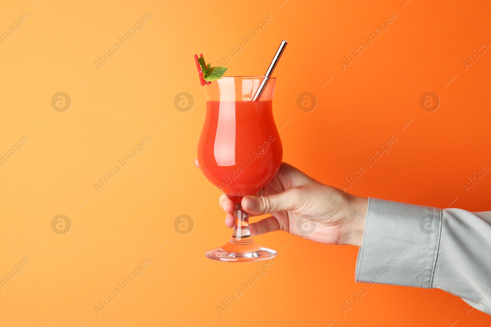 Photo of Woman with glass of refreshing cocktail on orange background, closeup