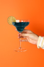 Photo of Woman with glass of refreshing cocktail on orange background, closeup