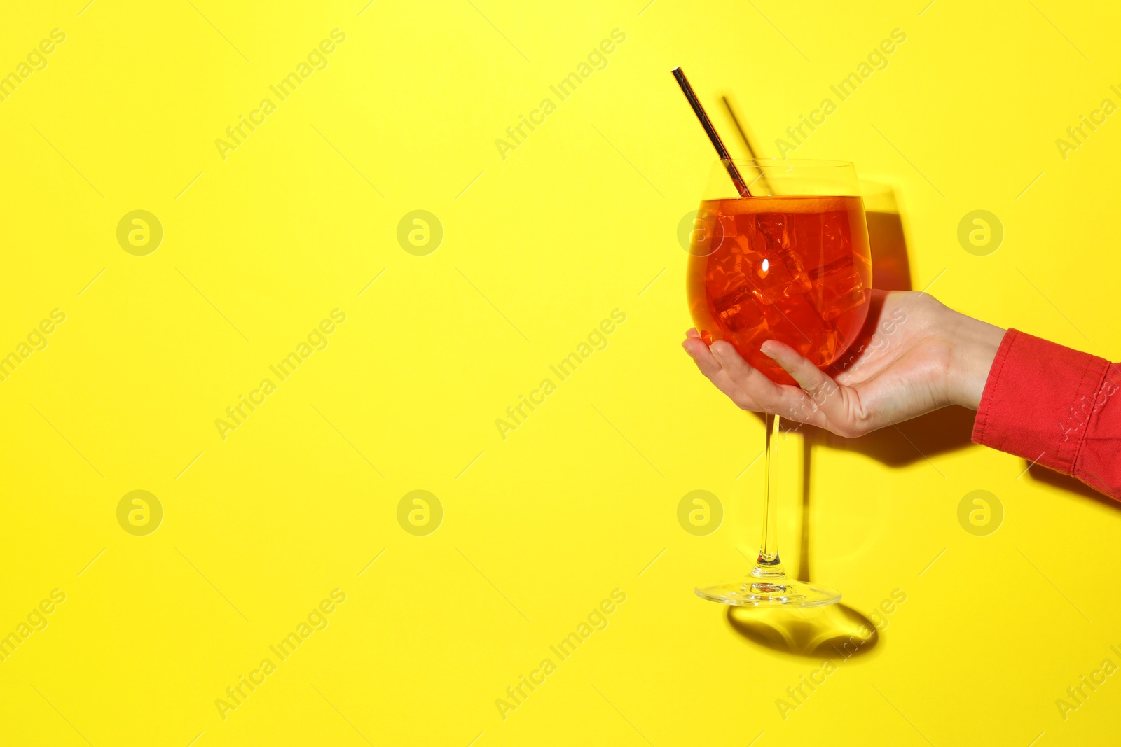 Photo of Woman with glass of refreshing cocktail on yellow background, closeup. Space for text