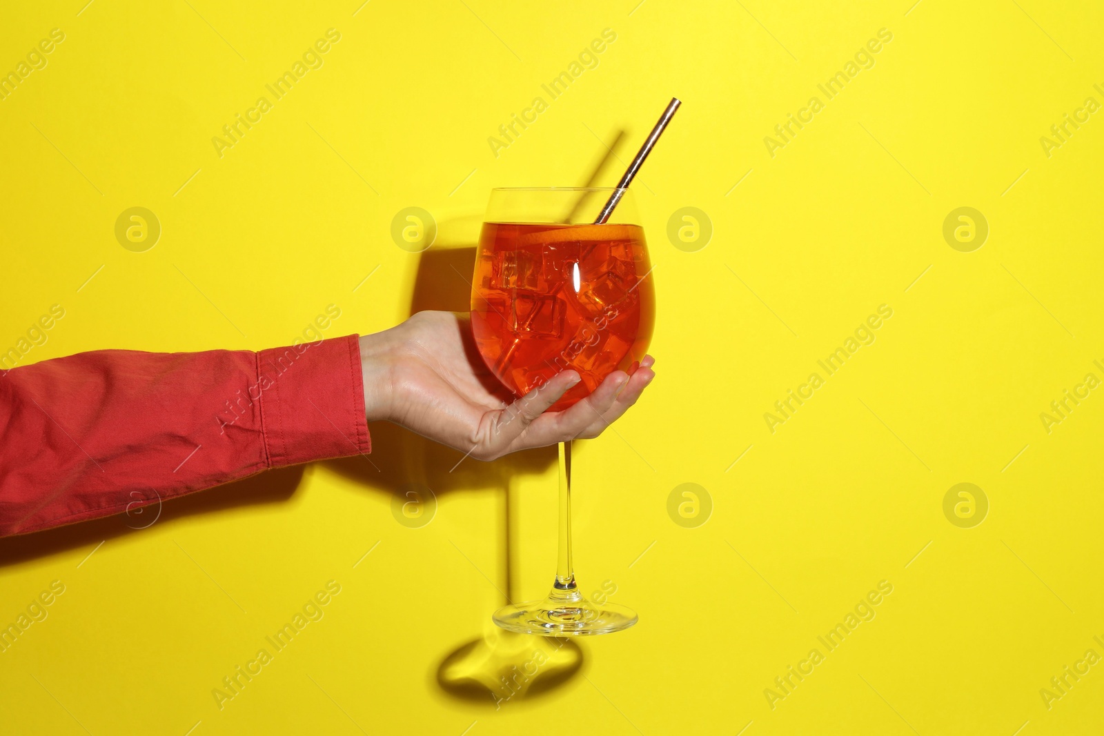 Photo of Woman with glass of refreshing cocktail on yellow background, closeup