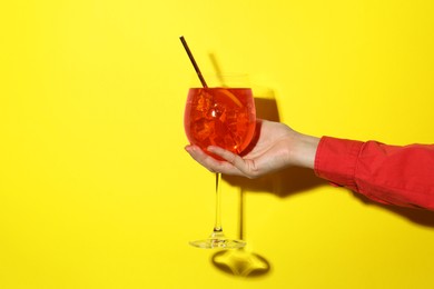 Photo of Woman with glass of refreshing cocktail on yellow background, closeup