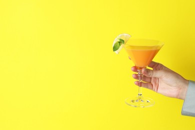 Photo of Woman with glass of refreshing cocktail on yellow background, closeup. Space for text