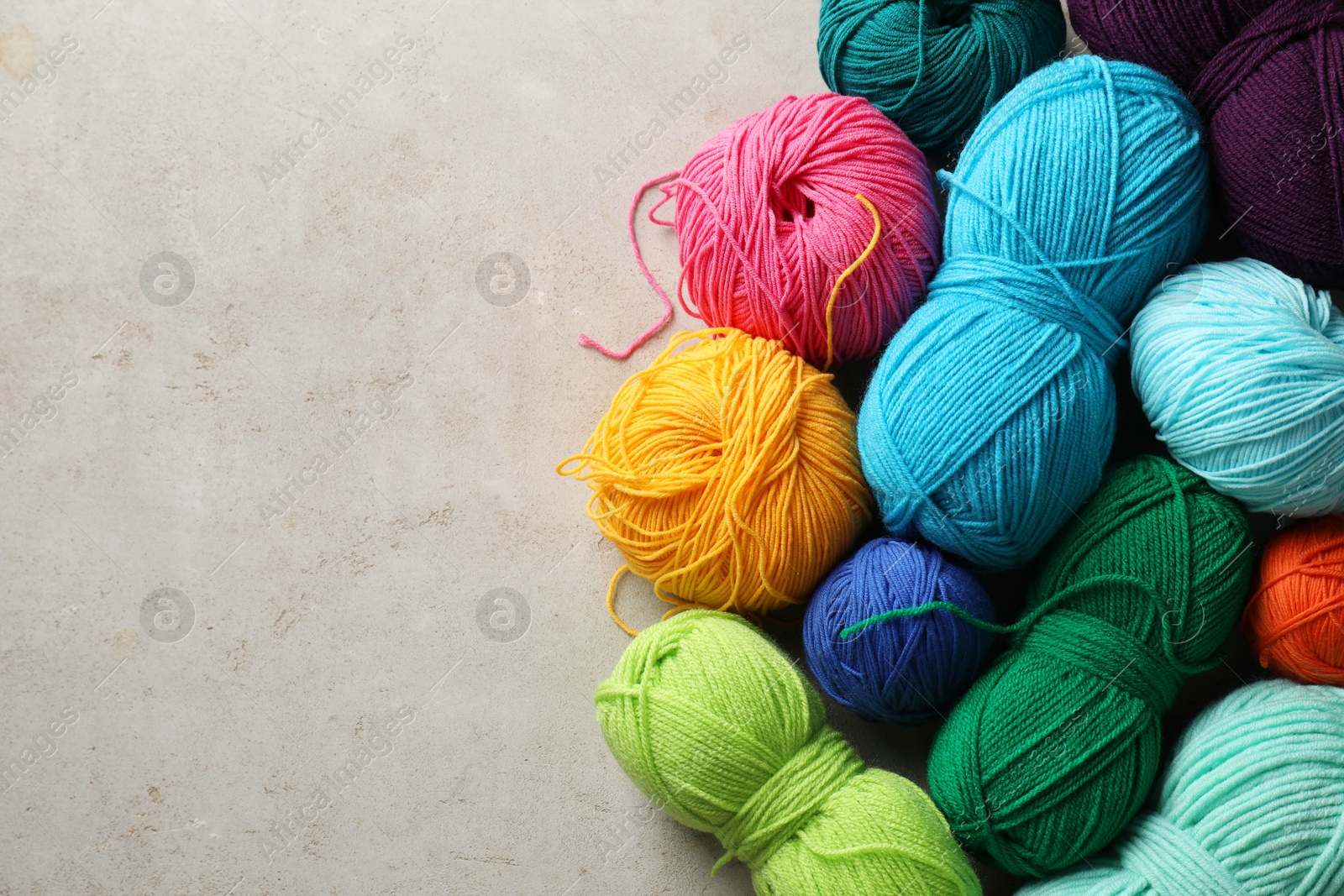 Photo of Different yarns on grey textured table, flat lay. Space for text