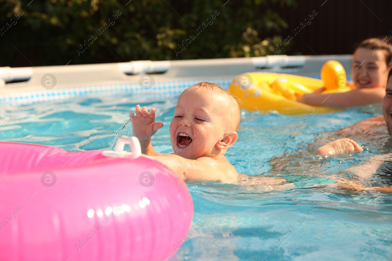 Photo of Parents and their son having fun in swimming pool outdoors