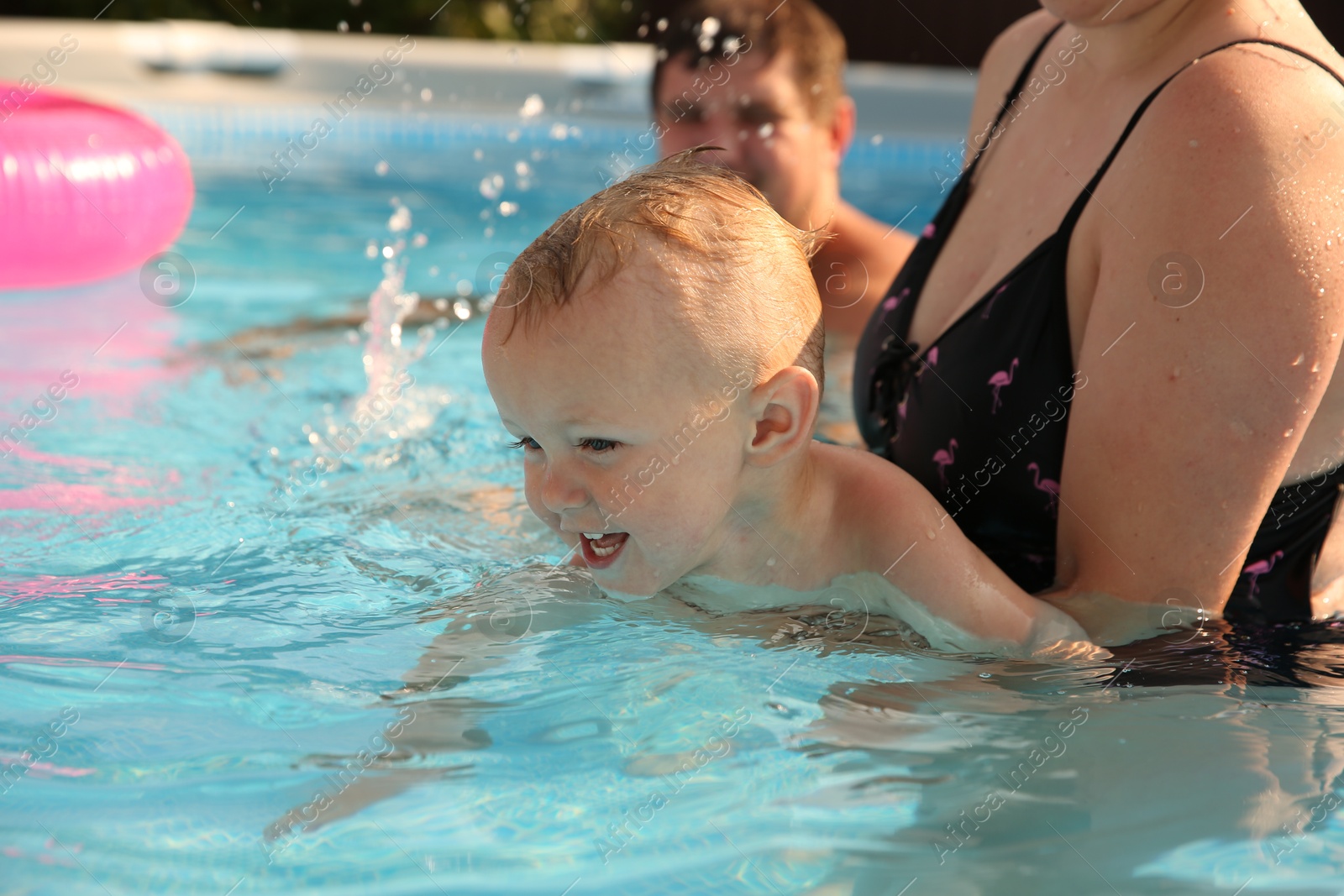 Photo of Parents and their son having fun in swimming pool outdoors