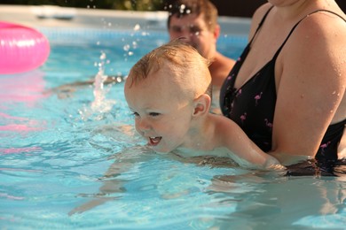 Parents and their son having fun in swimming pool outdoors