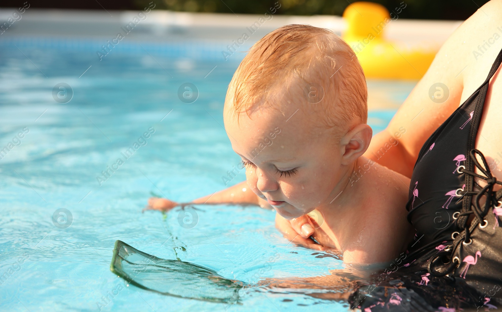 Photo of Mother and her son having fun in swimming pool outdoors, space for text