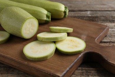 Photo of Board with fresh zucchinis on wooden table, closeup