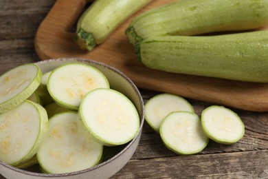 Photo of Fresh whole and cut zucchinis on wooden table, closeup