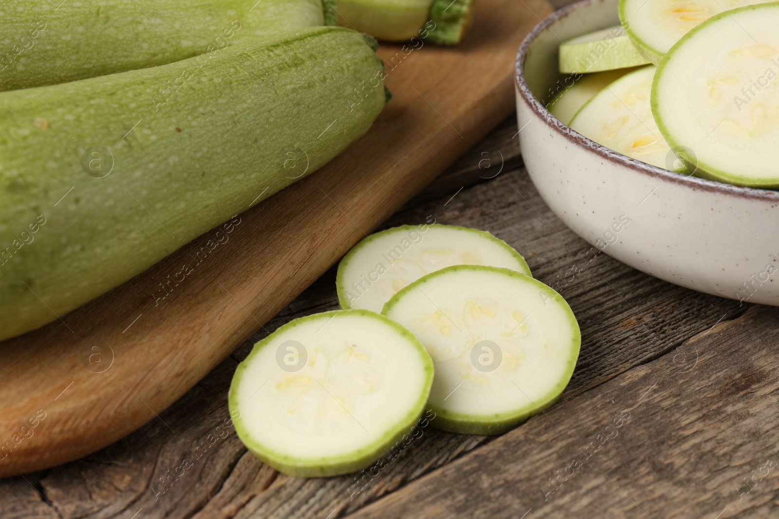 Photo of Fresh whole and cut zucchinis on wooden table, closeup