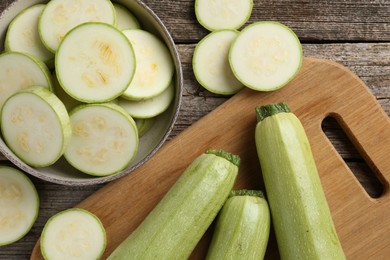 Photo of Fresh whole and cut zucchinis on wooden table, flat lay