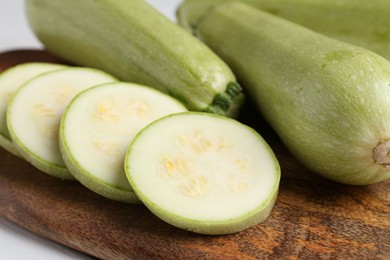 Photo of Board with fresh zucchinis on white table, closeup