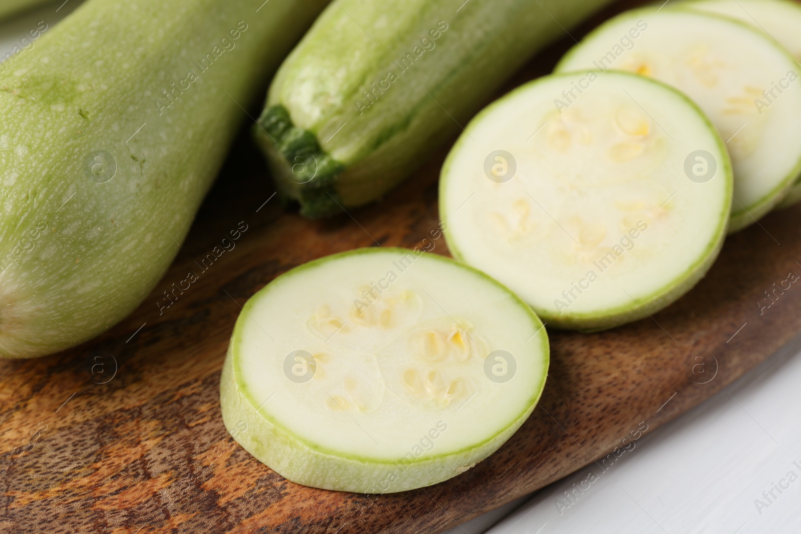 Photo of Board with fresh zucchinis on white table, closeup