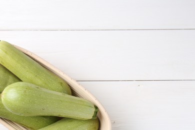 Photo of Fresh zucchinis on white wooden table, top view. Space for text