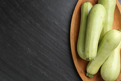 Photo of Fresh zucchinis on dark textured table, top view. Space for text