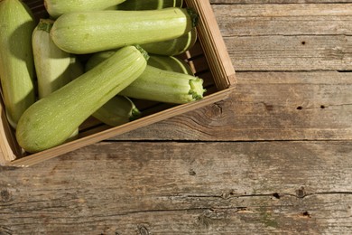 Photo of Crate with fresh zucchinis on wooden table, top view. Space for text